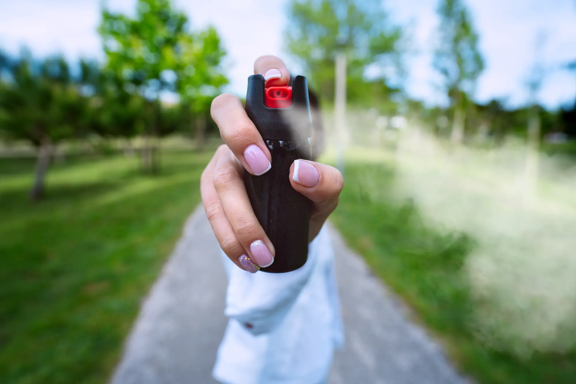 Woman using pepper spray for self defence outdoors