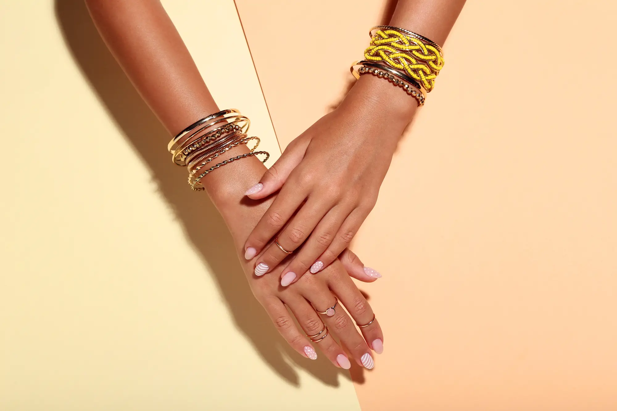 Female hands with bracelets and rings on colorful background